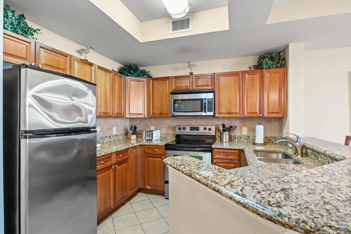 A beautifully staged kitchen and dining area with granite countertops, stainless steel appliances, and warm wood cabinetry. The open layout seamlessly connects the cooking space to the dining area, illustrating how meals and conversations flow together.