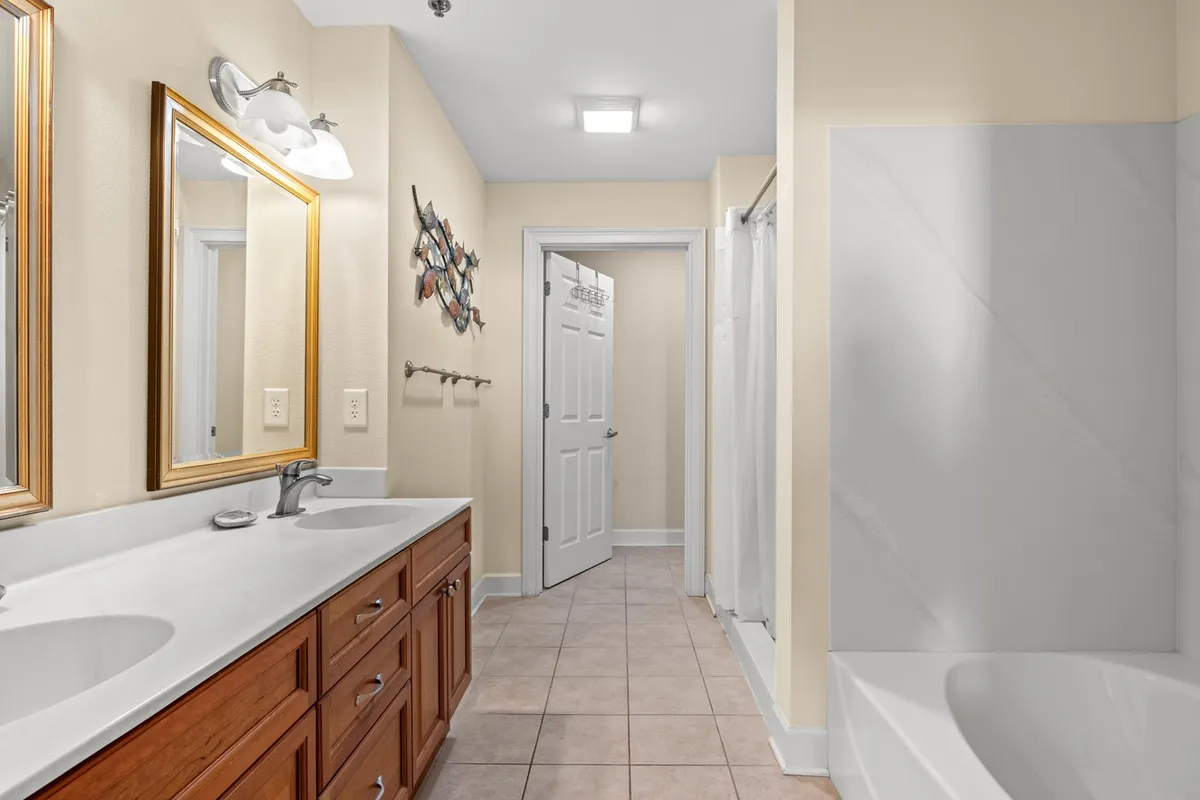 This bathroom features a spacious double vanity with mirrors, a shower area, soaking bathtub, and elegant framed wall art. The design is organized and tranquil, evoking a spa-like atmosphere perfect for unwinding.