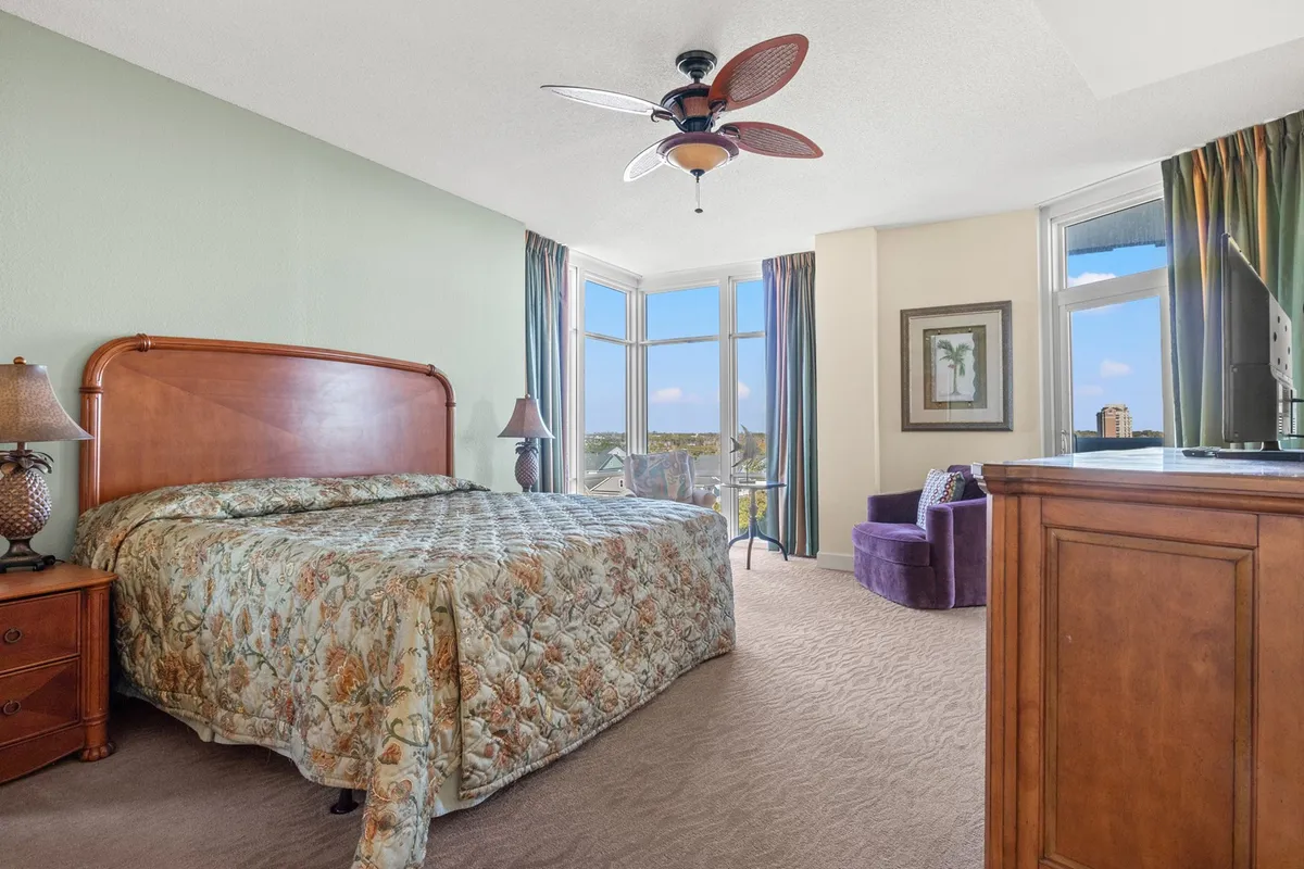 This image showcases a serene bedroom with a large, plush bed, expansive windows letting in natural light, a cozy armchair, and a nightstand for convenience. The calm colors and inviting textures convey a relaxing retreat ideal for unwinding after a day of adventure.